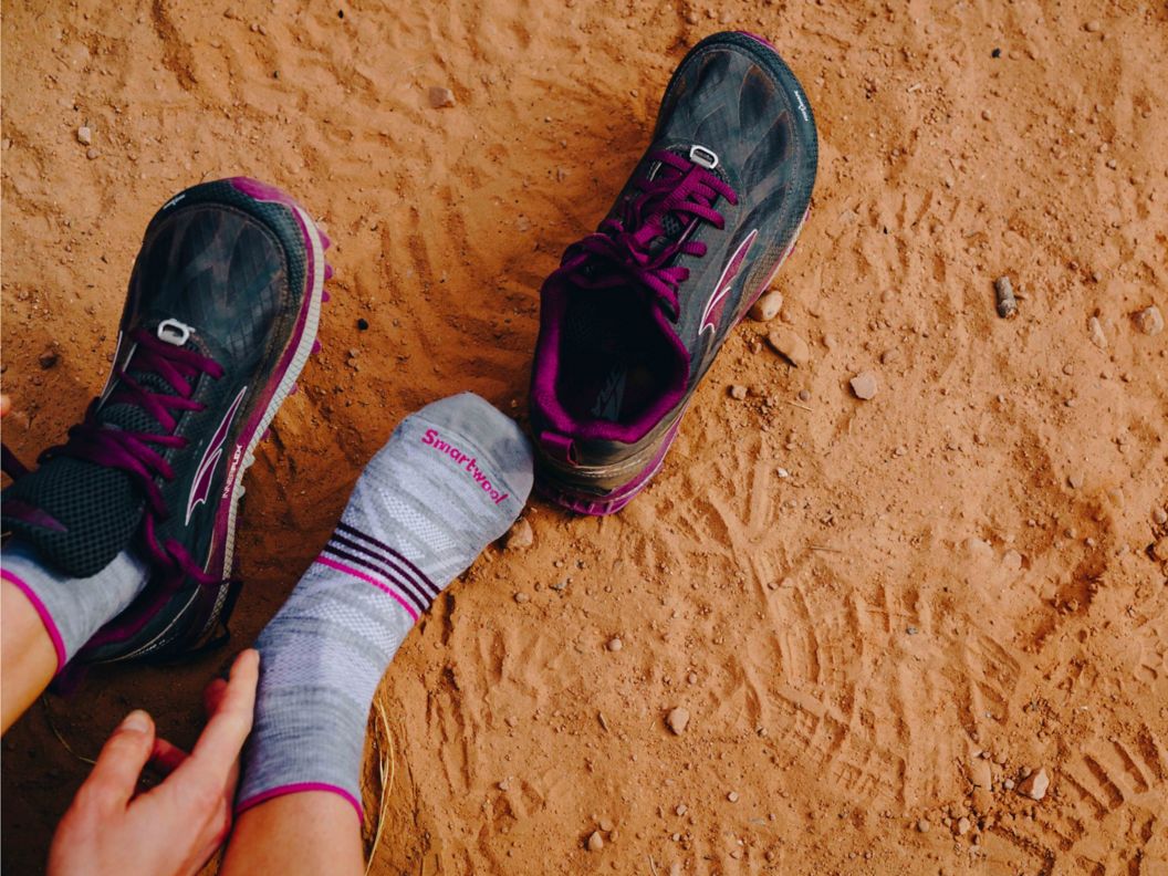 A person puts on a pair of trail running shoes. 